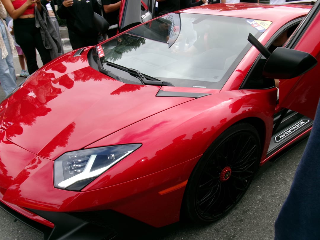 red lamborghini aventador sv, close on the headlight and front wheel, crowd behind