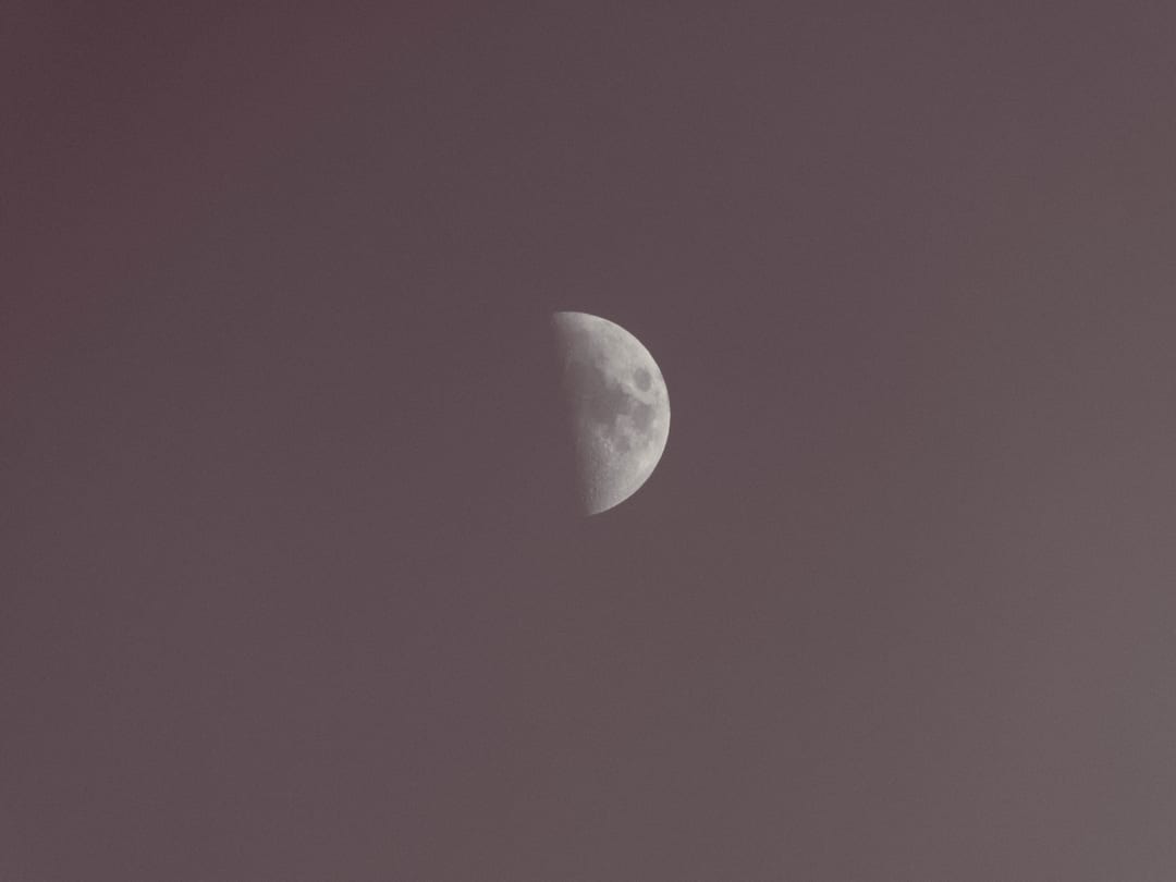 a half moon in a hazy dusk sky